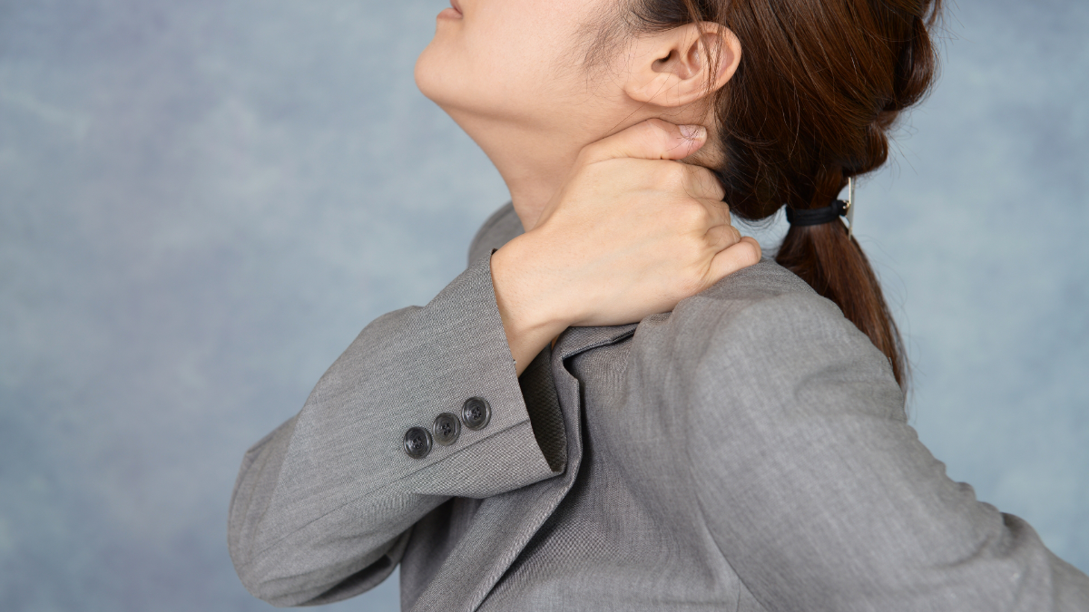 首に手を当てて伸ばすスーツの女性