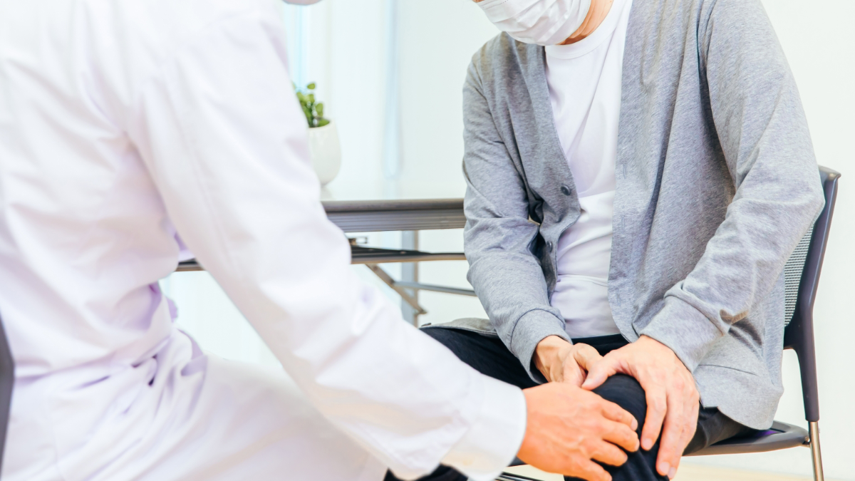 膝に痛みを感じている男性と診察をする医師